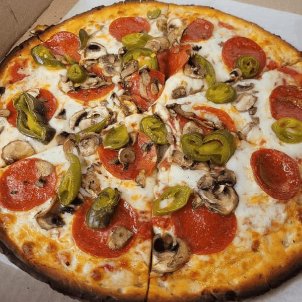 A whole pepperoni, mushroom, and green pepper pizza in a cardboard box.