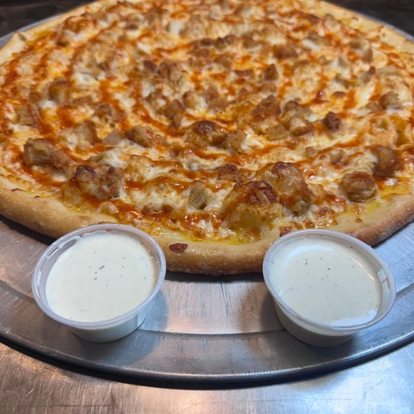A Joey's New York Pizza buffalo chicken pizza with two cups of ranch dressing on a metal tray.