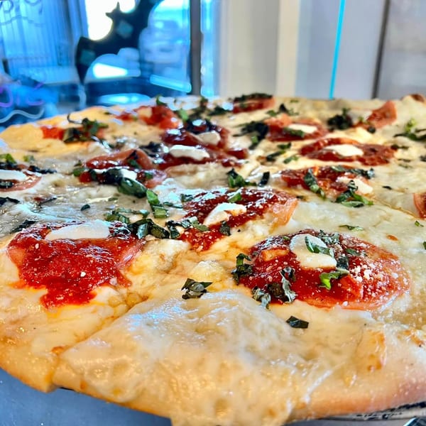 Close-up of a Joey's New York Pizza pie with melted cheese, red sauce, and fresh basil.
